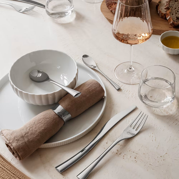 Georg Jensen 'Cobra' Tableware laid out on minimalist table setting. Unique Scandinavian designs