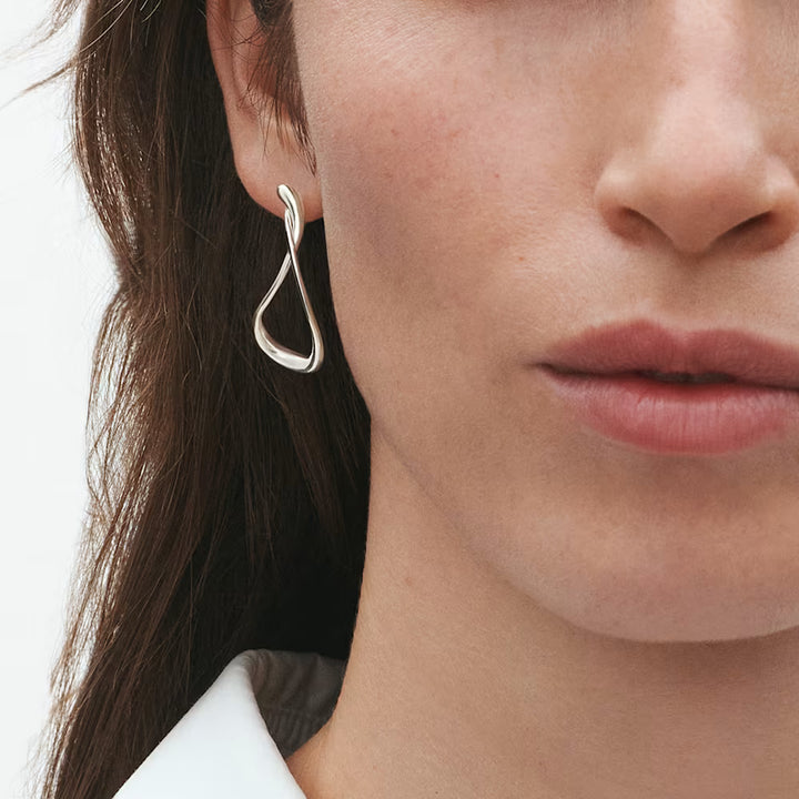 Pair of Georg Jensen Mercy silver hoops featuring flowing curves and an asymmetric silhouette
