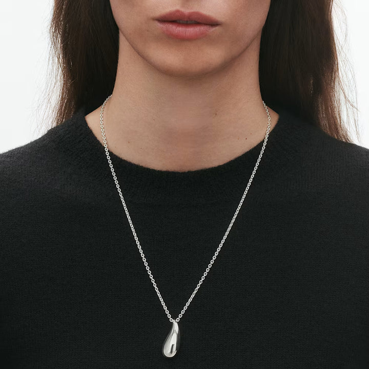 Lifestyle image of woman in black wearing Georg Jensen Reflect Sterling Silver drop-shaped Pendant and chain