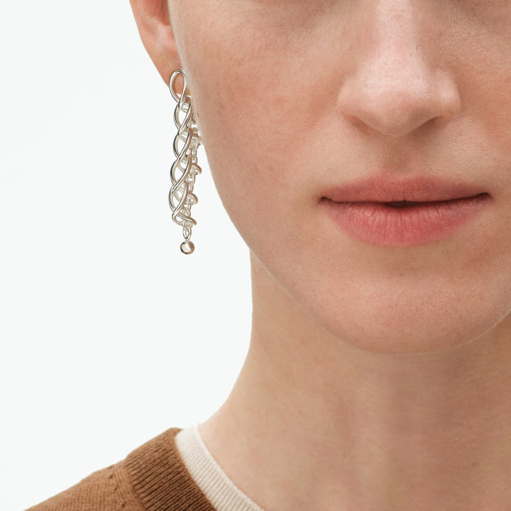 Close-up of Georg Jensen Weft Earrings featuring articulated silver links and hanging orb detail.